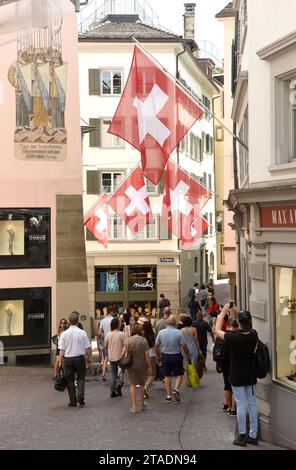 Zurigo, Svizzera - 3 giugno 2017: Persone per la strada di Zurigo decorate con bandiere della Svizzera. Bandiere svizzere sulla facciata dell'edificio a histori Foto Stock