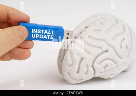 Un uomo inserisce un'unità flash nel suo cervello con la scritta - Install Update. Concetto di scienza e tecnologia. Foto Stock