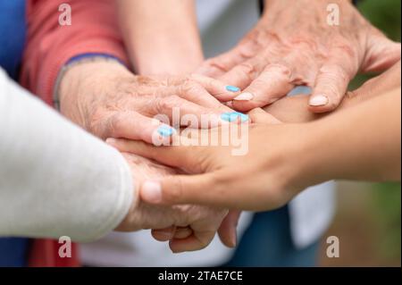 Concetto di famiglia, società che invecchia o lavoro di squadra, mani che mostrano unità nel mettere insieme le mani, mani anziane rughe degli anziani insieme ad altre mani giovani. Foto di alta qualità Foto Stock