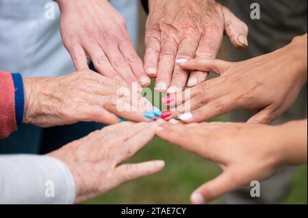 Concetto di famiglia, società che invecchia o lavoro di squadra, mani che mostrano unità nel mettere insieme le mani, mani anziane rughe degli anziani insieme ad altre mani giovani. Foto di alta qualità Foto Stock