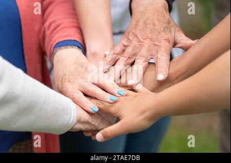 Concetto di famiglia, società che invecchia o lavoro di squadra, mani che mostrano unità nel mettere insieme le mani, mani anziane rughe degli anziani insieme ad altre mani giovani. Foto di alta qualità Foto Stock