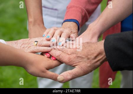 Concetto di famiglia, società che invecchia o lavoro di squadra, mani che mostrano unità nel mettere insieme le mani, mani anziane rughe degli anziani insieme ad altre mani giovani. Foto di alta qualità Foto Stock