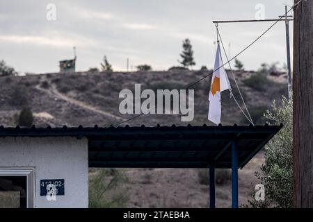 Nicosia, Nicosia, Cipro. 30 novembre 2023. La bandiera di Cipro si vede su un avamposto dell'esercito cipriota senza equipaggio con un avamposto dell'esercito turco sullo sfondo. L'esercito turco ha installato due giorni fa una macchina fotografica e le bandiere della Turchia e della cosiddetta "Repubblica turca di Cipro del Nord" sul tetto di una casa abbandonata, nota come "casa di Christalla", all'interno della zona cuscinetto delle Nazioni Unite, che ufficialmente è il territorio della Repubblica di Cipro, concesso volontariamente alle Nazioni Unite per motivi di mantenimento della pace. Dato che questo atto è in contrasto con lo status quo della zona cuscinetto, la Repubblica di Cipro ha chiesto alle truppe dell'ONU di agire conformemente Foto Stock