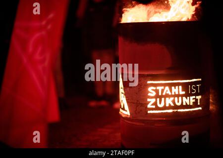 Duisburg, Germania. 30 novembre 2023. Un barile con l'iscrizione "l'acciaio è il futuro" può essere visto in una protesta nel corso dell'attuale disputa salariale. I sindacalisti delle acciaierie di Duisburg e le delegazioni dei rami circostanti simbolicamente suonano alla fine dell'obbligo di pace. I sindacalisti fanno una marcia con fiaccolata dal Hüttenschenke di Hüttenwerke Krupp Mannesmann alla piattaforma di osservazione della Tiger & Turtle a Duisburg. Credito: Fabian Strauch/dpa/Alamy Live News Foto Stock