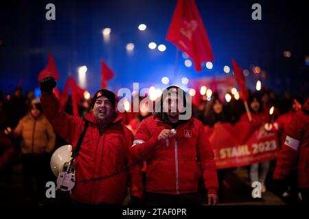 Duisburg, Germania. 30 novembre 2023. I partecipanti alla dimostrazione camminano verso la piattaforma di osservazione durante una protesta nel corso dell'attuale disputa salariale. I sindacalisti delle acciaierie di Duisburg e le delegazioni dei rami circostanti annunciano simbolicamente la fine dell'obbligo di pace. I sindacalisti fanno una marcia con fiaccolata dal Hüttenschenke di Hüttenwerke Krupp Mannesmann alla piattaforma panoramica di Tiger & Turtle a Duisburg. Credito: Fabian Strauch/dpa/Alamy Live News Foto Stock