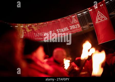 Duisburg, Germania. 30 novembre 2023. In occasione di una protesta nel corso dell'attuale contenzioso salariale, un cartello recita "Collective Bargaining round Steel 2023”. I sindacalisti delle acciaierie di Duisburg e le delegazioni dei rami circostanti simbolicamente suonano alla fine dell'obbligo di pace. I sindacalisti marciano con le torce dal Hüttenschenke di Hüttenwerke Krupp Mannesmann alla piattaforma panoramica di Tiger & Turtle a Duisburg. Credito: Fabian Strauch/dpa/Alamy Live News Foto Stock