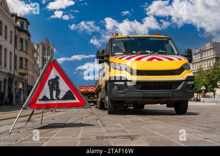 Segnaletica stradale rossa triangolare che indica la presenza di lavori sulla strada e sulle attrezzature da costruzione utilizzate nella costruzione di strade. Foto Stock