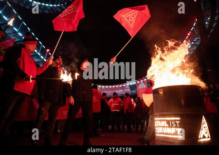 Duisburg, Germania. 30 novembre 2023. Partecipanti a un'azione IG Metall nel corso dell'attuale ondata di disputa salariale accanto a una canna da fuoco. I sindacalisti delle compagnie siderurgiche di Duisburg e le delegazioni delle filiali circostanti annunciarono simbolicamente la fine dell'obbligo di pace. Credito: Fabian Strauch/dpa/Alamy Live News Foto Stock