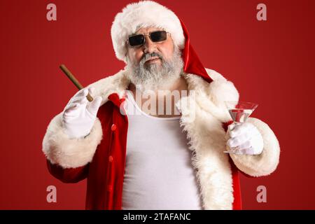 Babbo Natale cattivo con sigaro e cocktail su sfondo rosso Foto Stock