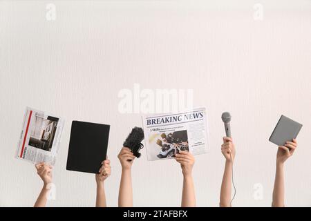 Mani femminili con giornali, microfoni e notebook su sfondo chiaro Foto Stock