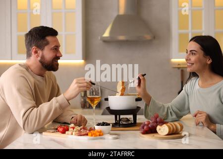 Coppia affettuosa che si gode la fonduta durante un appuntamento romantico in cucina Foto Stock