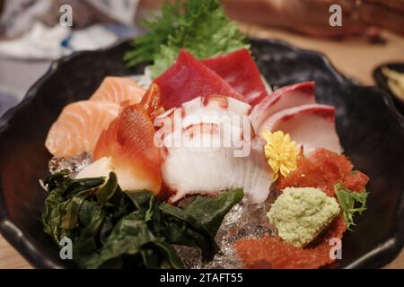 Vista dall'alto di Sashimi con varie fette di pesce fresco crudo, calamari e polpi, sul bancone di legno. Foto Stock