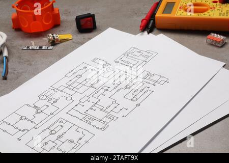 Schemi elettrici, multimetro digitale e altre apparecchiature elettriche su tabella grigia Foto Stock