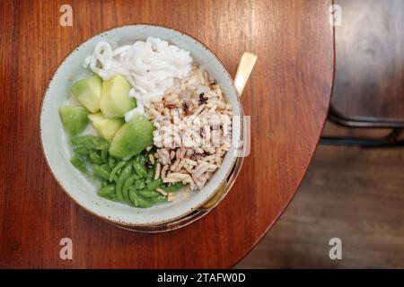 Vista ravvicinata e dall'alto presso la tazza di Lod Chong o Cendol, dessert dolce ghiacciato famoso nel sud-est asiatico, con riso smistato e cantalupe. Foto Stock