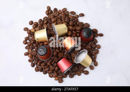 Molte capsule di caffè e chicchi su sfondo bianco, vista dall'alto Foto Stock