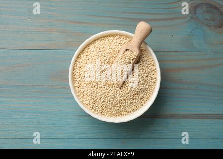 Asciugare i semi di quinoa e raccoglierli in un recipiente su un tavolo di legno azzurro, vista dall'alto Foto Stock