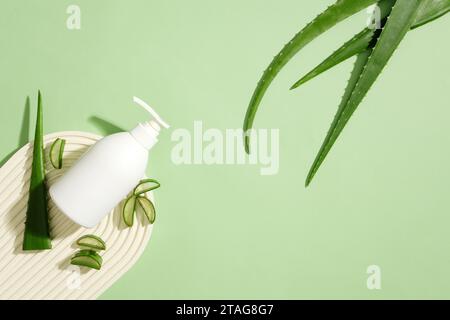 L'aloe vera fresca affettata viene esposta accanto a una bottiglia di gel doccia non etichettata su una piattaforma a forma di cupola. L'angolo superiore destro del telaio presenta una f Foto Stock