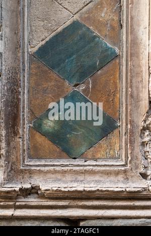 Due diamanti verdi e blu sono allestiti in una sezione di una vecchia porta malandata in Toscana, Italia Foto Stock