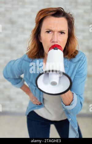 donna arrabbiata gridando nel megafono Foto Stock
