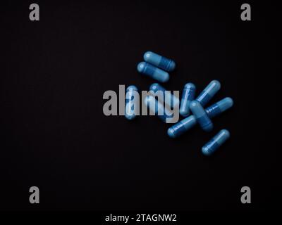 Capsule di aminoacidi su sfondo di carta scura. Messa a fuoco morbida. Vista dall'alto. Primo piano. Copia spazio. Foto Stock