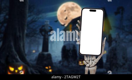 Uomo morto mano scheletrica che tiene lo smartphone mockup sul cimitero con luna piena, zucche, pipistrelli e casa oscura di notte, idea creativa di halloween. Hallowee Foto Stock