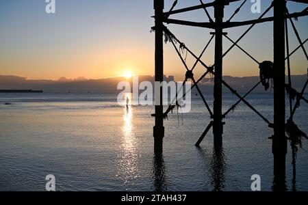 Brighton Regno Unito 1 dicembre 2023 - Un nuotatore emerge dal mare sfidando le condizioni di congelamento del molo di Brighton Palace all'alba questa mattina dopo la notte più fredda della stagione finora in tutta la Gran Bretagna : Credit Simon Dack / Alamy Live News Foto Stock