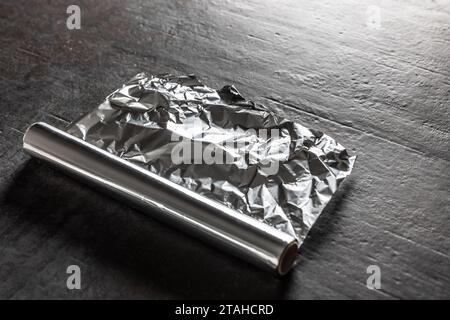 Foglio di alluminio su fondo di cemento scuro. Foto Stock