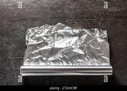 Foglio di alluminio su fondo di cemento scuro. Foto Stock