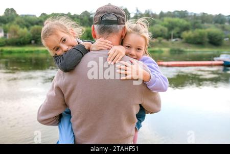 Il padre porta due figlie in braccio quando giocano nel parco Foto Stock