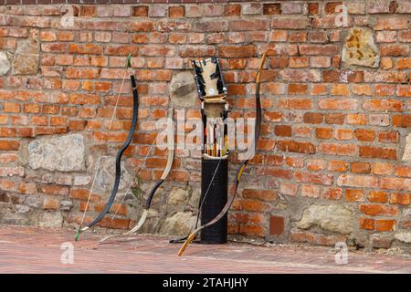 Archi e frecce appoggiate contro un muro di mattoni Foto Stock