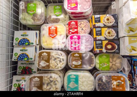 Italia - 26 novembre 2023: Gelati di vario gusto in vasche di plastica di varie marche esposti in bancone refrigerato in vendita in superm Italiano Foto Stock