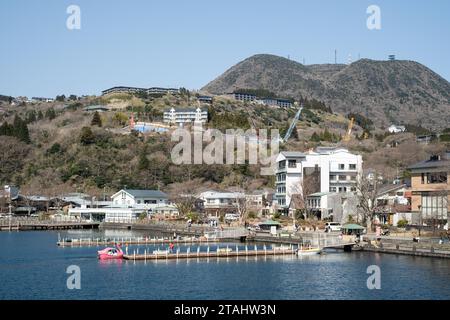 Jetties sul lago Ashi, con città e vette alle spalle, Hakone, Giappone. Foto Stock