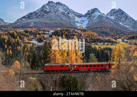 Ftan, Svizzera - novembre 06. 2022: Il treno rosso della ferrovia Retica passa con il castello di Tarasp sullo sfondo, Canton Grigioni Foto Stock