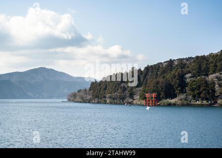 Monte Fuji appena visibile in lontananza dietro la porta Torii per il santuario Hakone sulla riva del lago Ashinoko, Hakone, Giappone. Preso da a bordo del Foto Stock