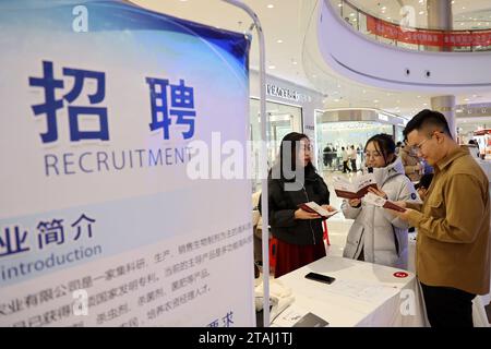 BINZHOU, CINA - 1° DICEMBRE 2023 - chi cerca lavoro cerca informazioni sull'occupazione in una fiera del lavoro per i laureati a Binzhou, nello Shandong della Cina orientale Foto Stock