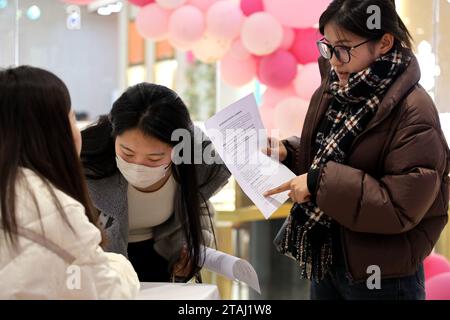 BINZHOU, CINA - 1° DICEMBRE 2023 - chi cerca lavoro cerca informazioni sull'occupazione in una fiera del lavoro per i laureati a Binzhou, nello Shandong della Cina orientale Foto Stock