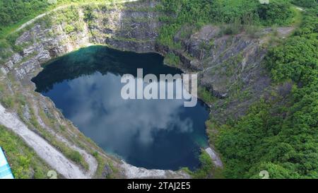 Una vista aerea di un lussureggiante paesaggio verde con un grande cratere pieno di lago al centro Foto Stock