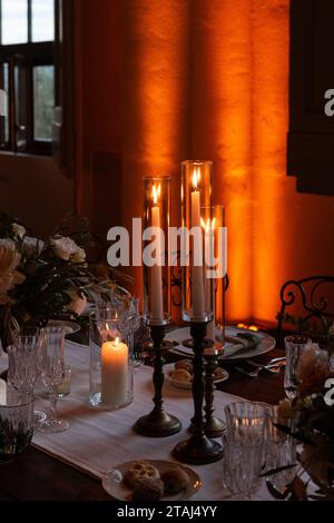 Le luci a lume di candela e le luci soffuse creano un'atmosfera calda e romantica nella sala banchetti per un grande matrimonio italiano. Foto Stock