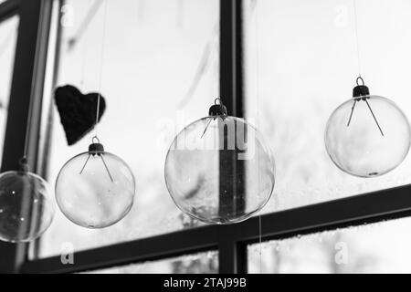 Palle di vetro trasparente appese di fronte a una finestra, foto astratta in bianco e nero decorata a Natale Foto Stock