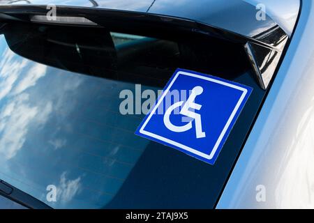 Adesivo sul finestrino di un'auto con pittogramma di una persona disabili su una sedia a rotelle. Concetti di trasporto e mobilità delle persone con disabilità Foto Stock