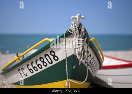 Yport, Francia - 21 luglio 2022: La parte anteriore di un piccolo peschereccio bianco verde che giace sulla spiaggia di Yport, giorno di sole in estate, corda Foto Stock