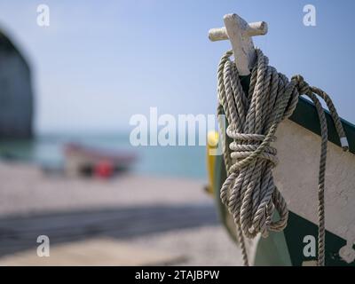 Yport, Francia - 21 luglio 2022: La parte anteriore di un piccolo peschereccio bianco verde che giace sulla spiaggia di Yport, giorno di sole in estate, corda Foto Stock