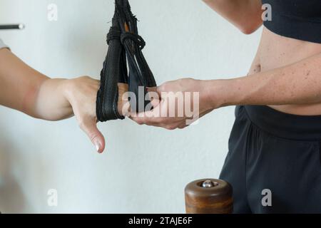 Primo piano di mani femminili caucasiche irriconoscibili durante l'allenamento della puleggia al chiuso, concetto di salute. Foto Stock