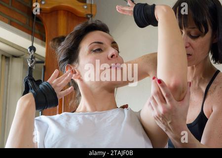 Primo piano di una formatrice caucasica adulta in piedi braccio toccante della sua studentessa che corregge i suoi movimenti durante l'addestramento e la lezione con exercis Foto Stock