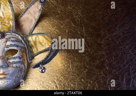 Vista dall'alto dell'elegante maschera di carnevale veneziana dorata su una superficie dorata. Spazio di copia per il testo. Foto Stock