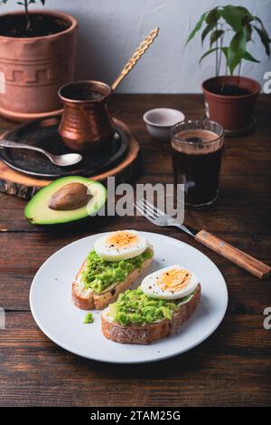 Due toast di avocado con fette di uovo bollito su piatto bianco Foto Stock