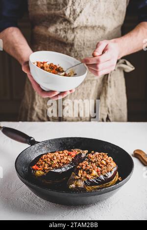 Preparazione delle melanzane farcite con carne macinata, pomodori e spezie. Piatto tradizionale Karniyarik di cucina turca Foto Stock