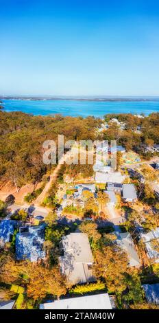 Case residenziali di lusso nella località turistica costiera australiana sulla spiaggia di Murrays, sul lago Macquarie, in un panorama verticale aereo. Foto Stock