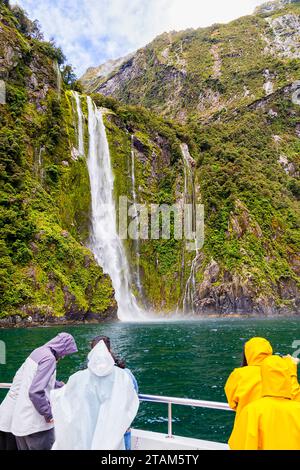 Milford Sound fiordland in nuova Zelanda - la fusione di Stirling cade dai turisti di una nave da crociera in cappotti impermeabili. Foto Stock