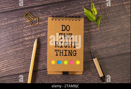 Fate la cosa giusta. Postazione di lavoro con blocco note e occhiali con penna su un tavolo di legno. testo sulla pagina. Foto Stock